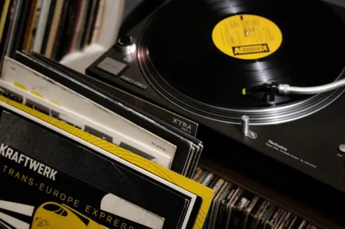 A close-up of vintage vinyl records fanned out beside a classic turntable, warm collectors ambiance, moody editorial lighting, shallow depth of field